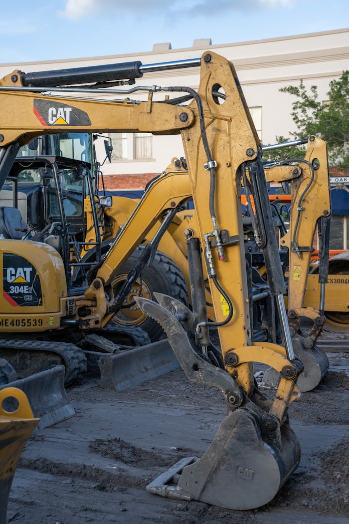 Services Yellow excavators at a construction site with machinery and equipment in the foreground.