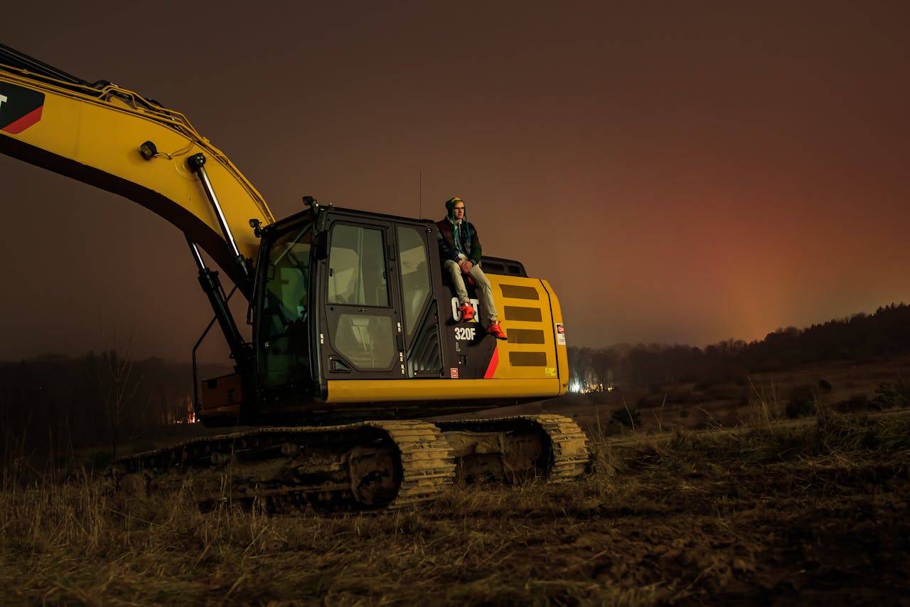 Services A person sitting on an excavator during the night in Greenville, Michigan. Tranquil rural setting.